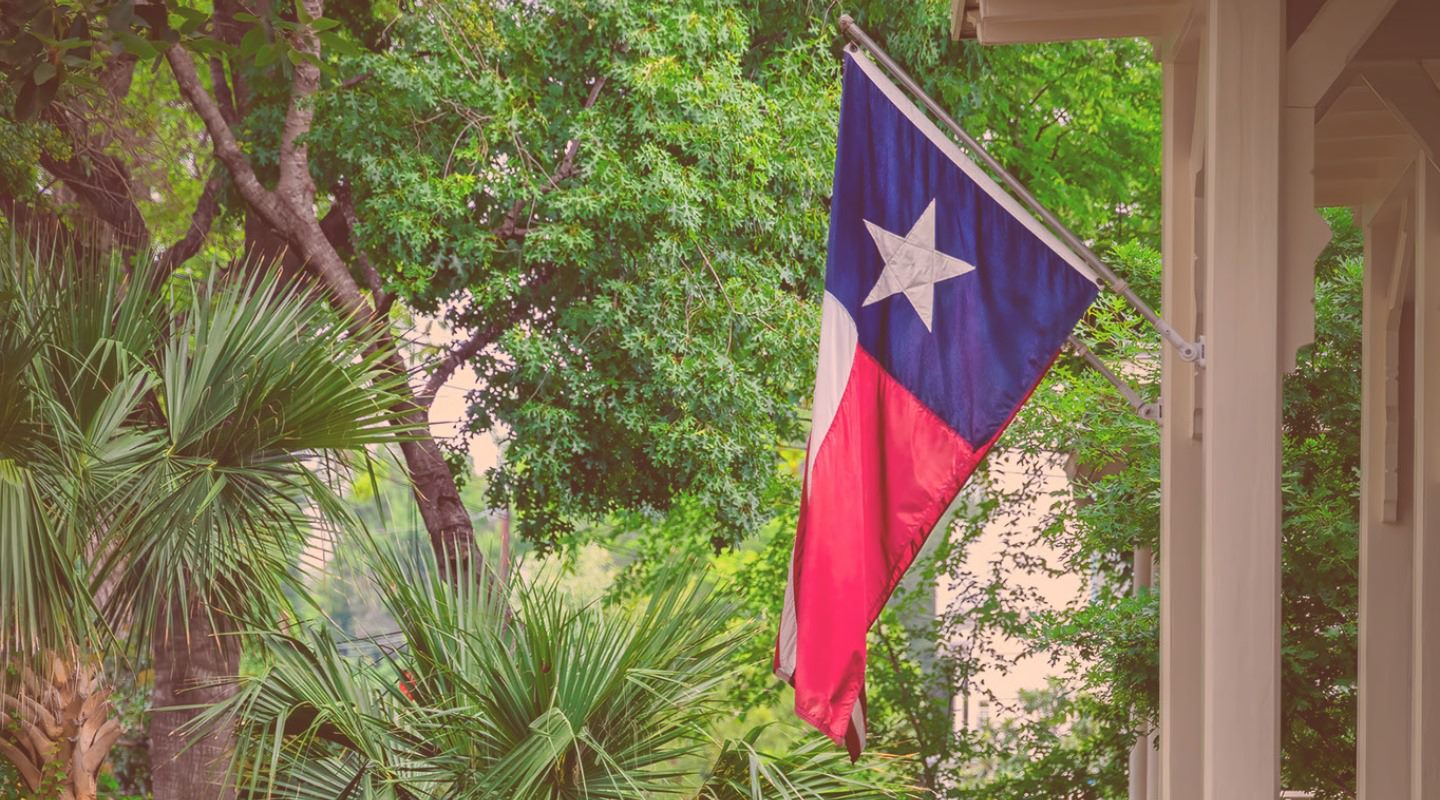 Picture of Texas Flag hanging from flag pole attached to the a porch